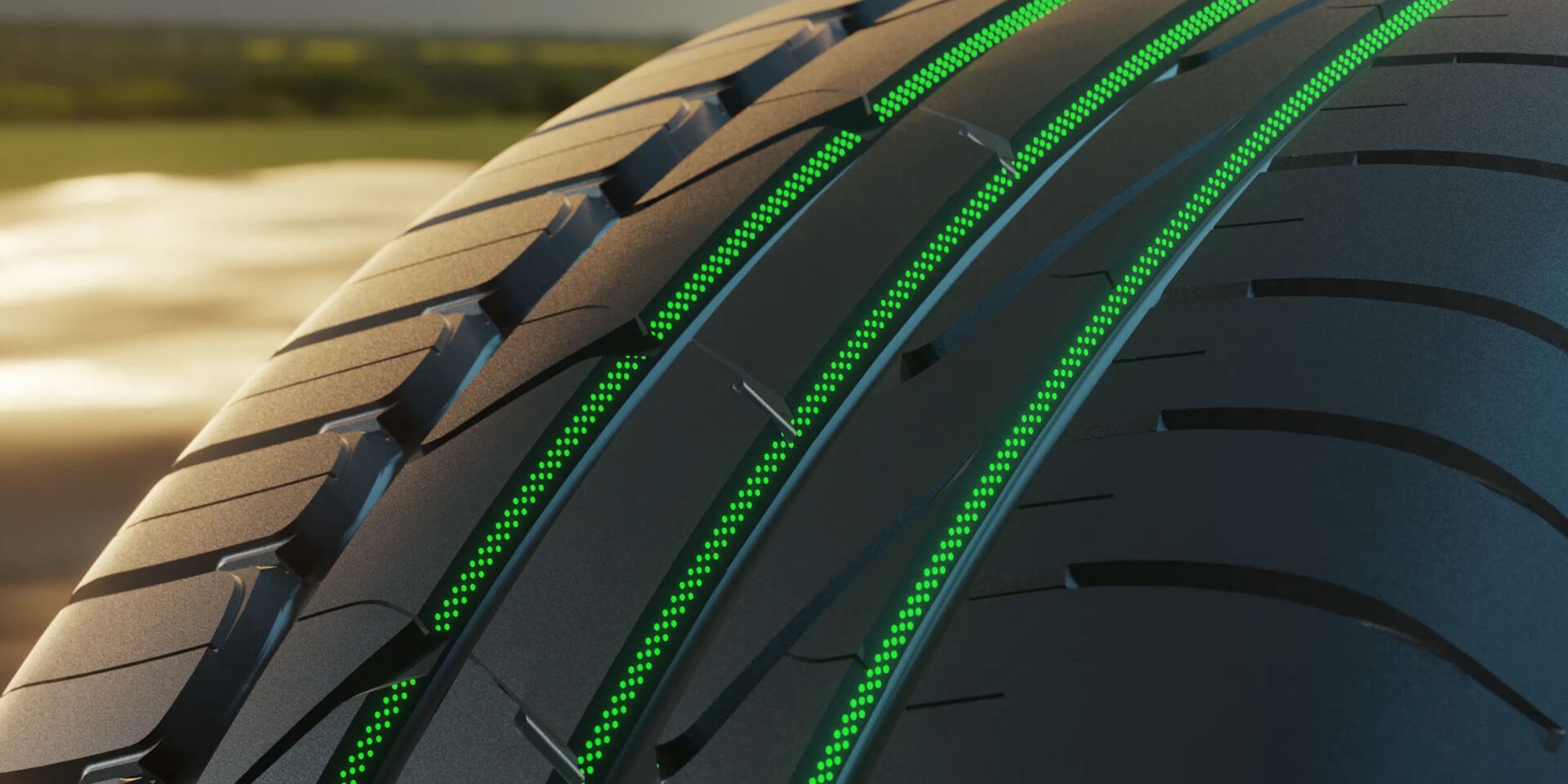 Gros plan en biais sur une bande de roulement à quatre rainures longitudinales, nervures continues et courtes entailles, avec des marquages verts superposés dans les sillons.