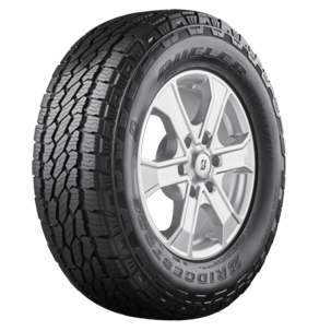 Pneumatique monté sur une jante, photographié en trois quarts sur fond blanc, avec une sculpture à blocs imbriqués et épaules entaillées.